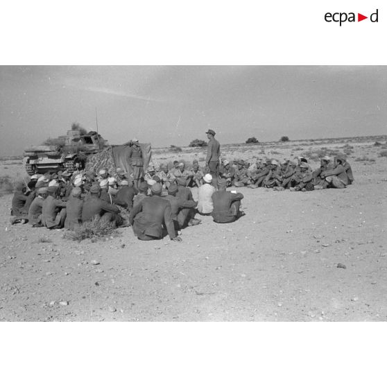 Des soldats de la 6e compagnie du Panzer Regiment 5 (Pz.Rgt-5) sont réunis en demi-cercle devant une tente et un char Panzer III (Pz-III Ausf H).