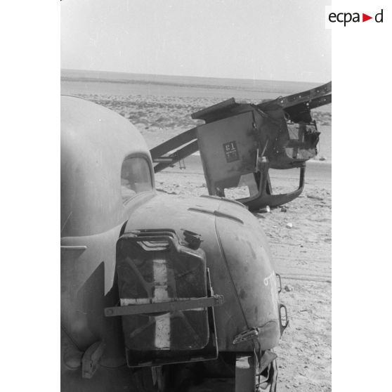 Des hommes du 155e Panzer Artillerie Regiment (Pz.Art.Rgt-155) cuisinent et changent une roue de leur véhicule tandis que des camions passent sur la route