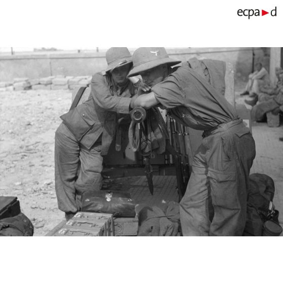 Deux artilleurs allemands devant un canon de DCA de 2 cm FlaK 30 qui vient d'être déchargé sur le quai du port de Tripoli.