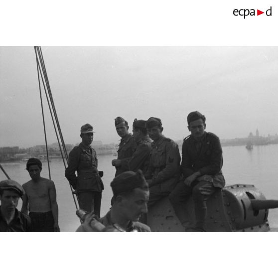 Troupes germano-italiennes sur un char italien M13/40 lui même encore chargé sur un navire dans le port de Tripoli.