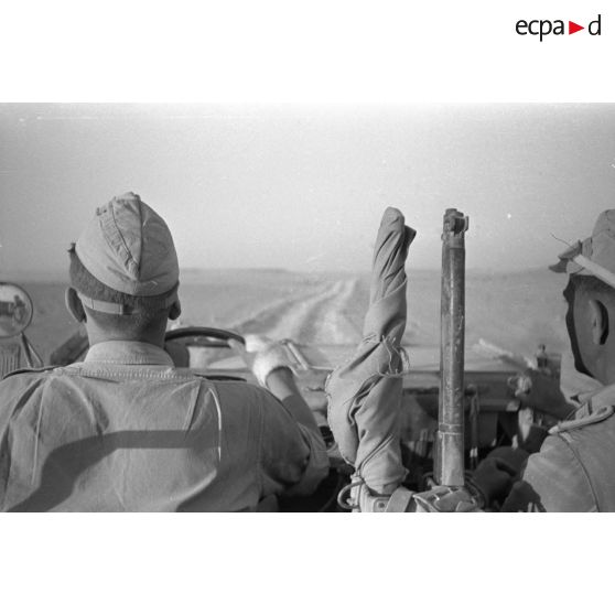 Le photographe qu'on aperçoit dans le rétroviseur, photographie le chauffeur et le chef de bord d'une Horch Kfz.15, un fusil britannique Lee-Enfield est posé au centre du véhicule.