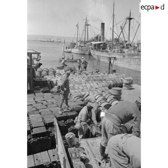 Activités dans le port de Tobrouk, déchargement d'essence (jerrycans et futs) par des prisonniers alliés.