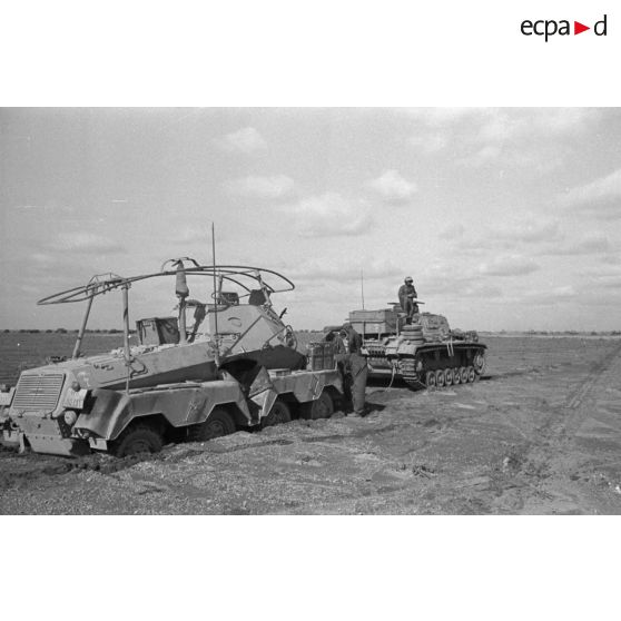 Un véhicule de reconnaissance Sd.Kfz 263 (8 RAD) s'est embourbé, un char Panzer III le tracte.