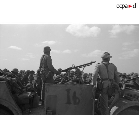 Dans le désert, un rassemblement de prisonniers britanniques sous la garde d'un Horch 108 armé d'une mitrailleuse MG-34.