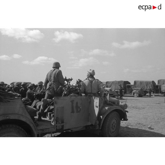 Dans le désert, un rassemblement de prisonniers britanniques sous la garde d'un Stoewer typ 40 armé d'une mitrailleuse MG-34.