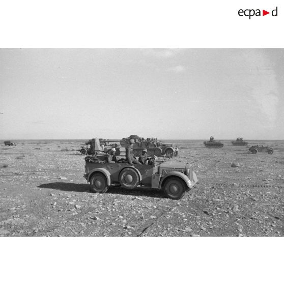 Une voiture de commandement Kfz.21 transportant le général Neumann-Silkow, en arrière plan un semi-chenillé Sd.kfz.7 tractant une pièce de 8,8 cm FlaK.