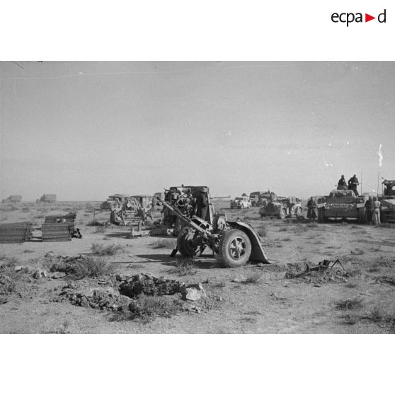 Une pièce de 8,8 cm FlaK déployée et sa remorque fait face à une colonne blindée allemande.