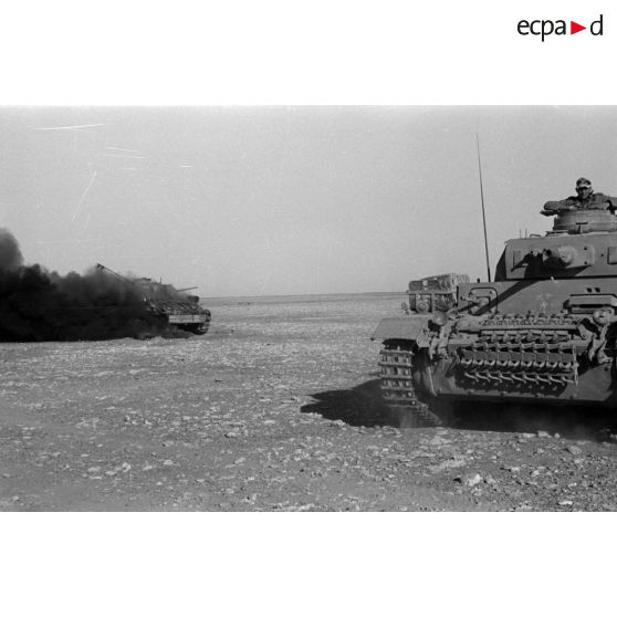 Un Panzer III de commandement (Befehlpanzer III) se rapproche d'un char britannique Matilda en feu.