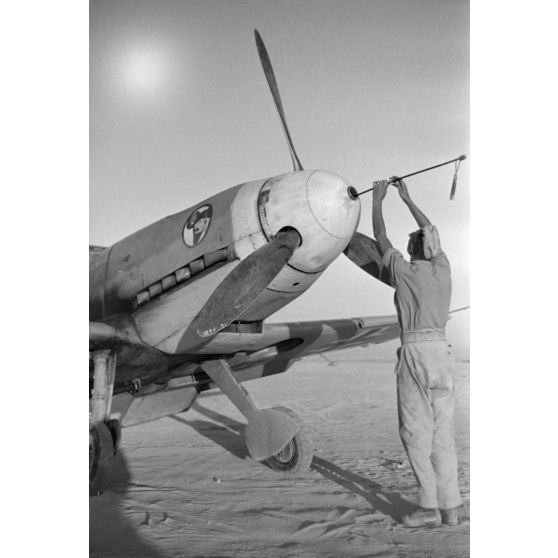 Un mécanicien du Jagdgeschwader 27 nettoie le canon du nez d'un chasseur Messerschmitt Bf-109.