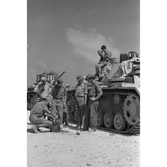 Repas de deux équipages de chars Panzer III progressant dans un désert égyptien.