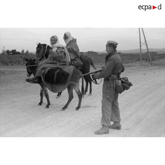 Un parachutiste sur une route de Tunisie croise la route de deux paysans.