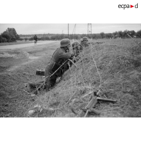 Des fantassins allemands en position défensive, au premier plan un mitrailleur équipé d'une MG-34.