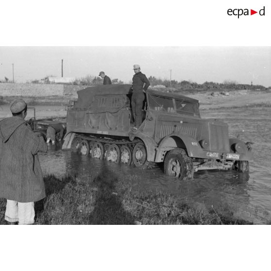 Dépannage d'un véhicule britannique par un semi-chenillé Sd.kfz.7, on note l'inscription Gruppe Hägele sur le blindé allemand.