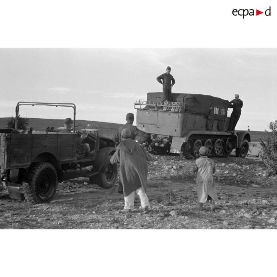 Dépannage d'un véhicule britannique par un semi-chenillé Sd.kfz.7, on note l'inscription Gruppe Hägele sur le blindé allemand.