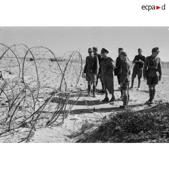 Le général (Generalleutnant) Erwin Rommel inspecte un réseau de fils barbelés en compagnie d'officiers allemands et italiens.