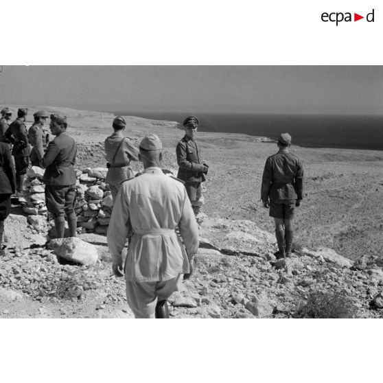 Le général Erwin Rommel, accompagné d'officiers italiens et allemands, observe la mer à partir d'une position retranchée italienne.