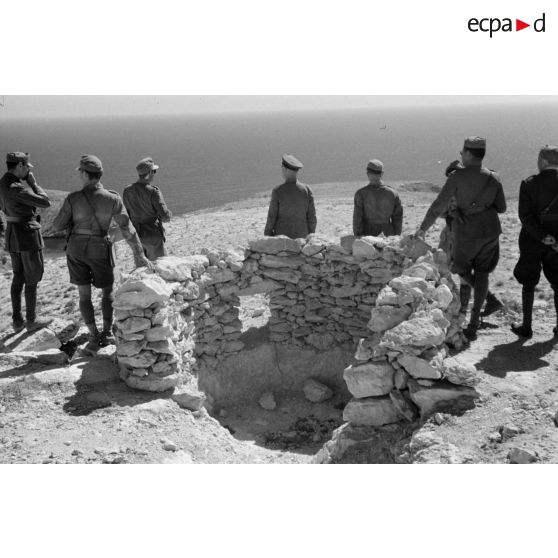 Le général Erwin Rommel, accompagné d'officiers italiens et allemands, observe la mer à partir d'une position retranchée italienne.