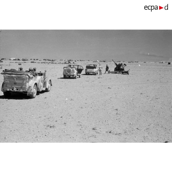 Des voitures Kfz-15, Kfz-21 et Kfz-3 qui composent l'état-major de Rommel près d'un camp et de canons italiens.