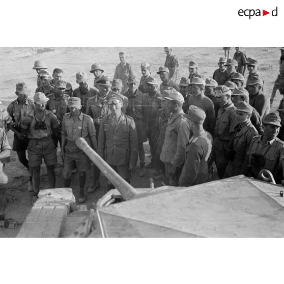 En compagnie de son état-major, le général Erwin Rommel inspecte un char britannique Crusader ou Cruiser détruit.