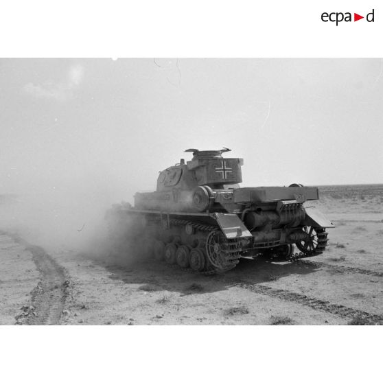 Un char Panzer IV (Pz-IV Ausf-E) à tourelle Ausf-D du Panzer-Regiment 5 (Pz.Rgt-5) de la 21e division blindée allemande (21-Pz.Div.) roule dans le désert.