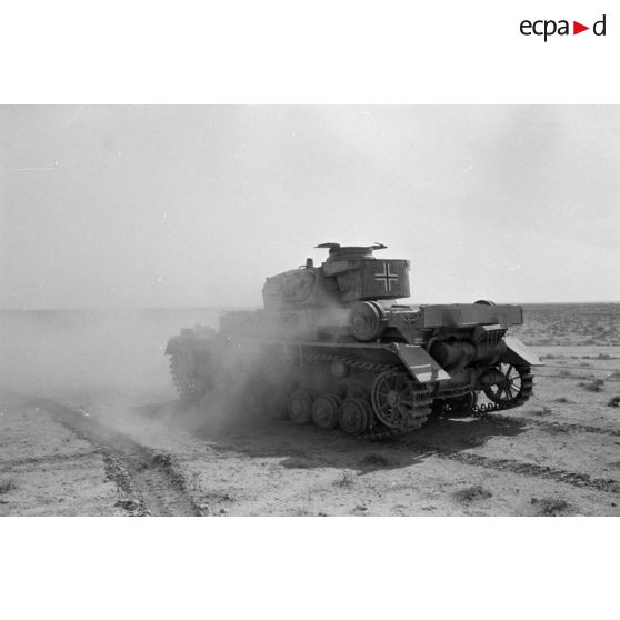 Un char Panzer IV (Pz-IV Ausf-E) à tourelle Ausf-D du Panzer-Regiment 5 (Pz.Rgt-5) de la 21e division blindée allemande (21-Pz.Div.) roule dans le désert.