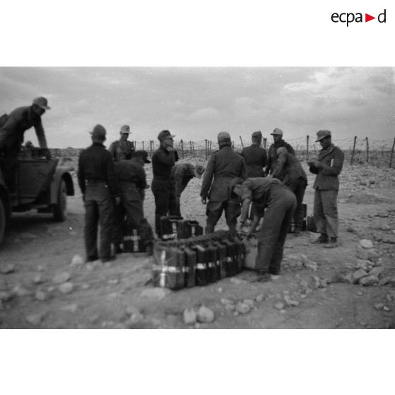 Des soldats déchargent le Kfz-15 tandis que d'autres fument.