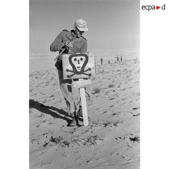 Un soldat installe le panneau prévenant de la présence d'un champ de mines.