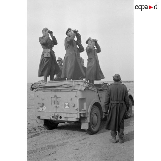 Le général (General der Panzertruppe) Erwin Rommel et les officiers de son état-major observent le terrain, à la jumelle, certains sont debout dans une voiture Kfz-15.