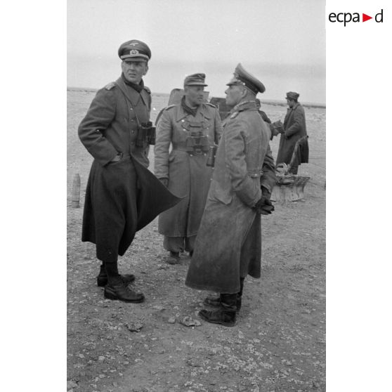 Lors de la mise en batterie du canon italien, le général Erwin Rommel et le colonel (Oberstleutnant) Westphal discutent devant un officier de la Luftwaffe.