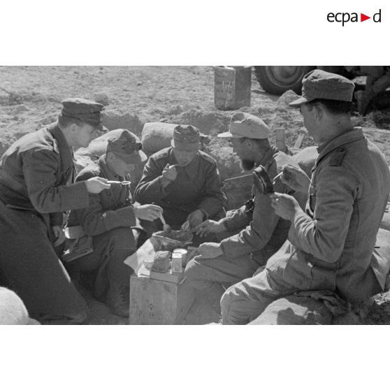 Un groupe de soldats mange confortablement installé dans un trou.