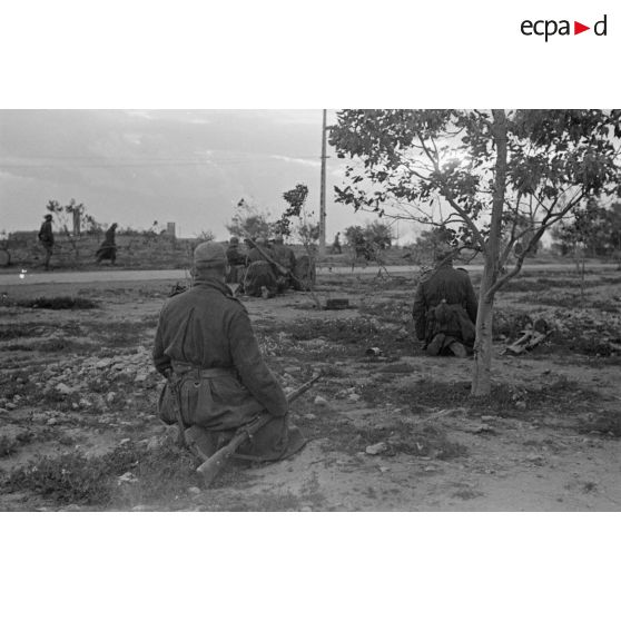 Des soldats sont accroupis près de la route derrière un canon de 3,7 cm PaK en batterie.