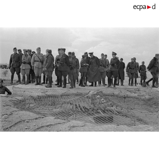 Le groupe d'officiers inspecte une position d'artillerie, il pourrait s'agir d'une position de télémètre camouflée sous un filet.