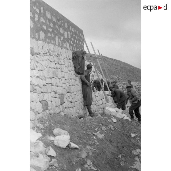 Au fort de Mechili, des soldats italiens reconstruisent un mur éboulé.