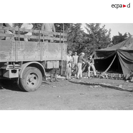 Des soldats déchargent du pain d'un camion et l'entreposent sous une tente.