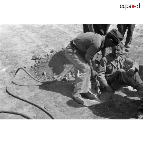 Les soldats italiens creusent un trou à l'aide d'un marteau-piqueur.