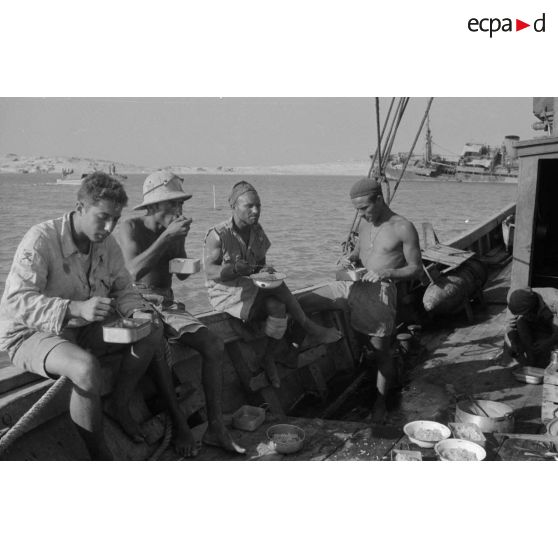 Des soldats italiens mangent sur le pont d'un bateau.