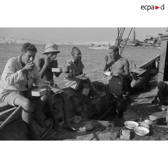 Des soldats italiens mangent sur le pont d'un bateau.