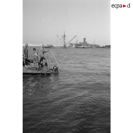 Travail d'une équipe autour d'un scaphandrier allemand qui plonge dans les eaux du port.