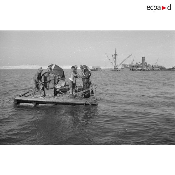 Travail d'une équipe autour d'un scaphandrier allemand qui plonge dans les eaux du port.