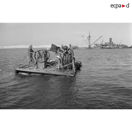 Travail d'une équipe autour d'un scaphandrier allemand qui plonge dans les eaux du port.