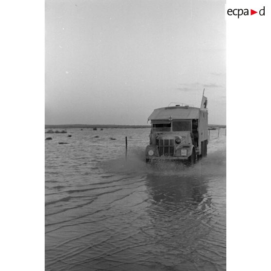 Passage de véhicules sur une piste inondée.