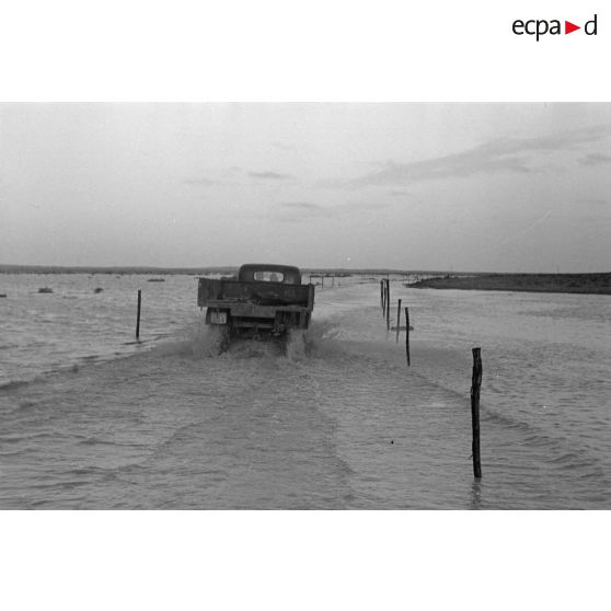 Passage de véhicules sur une piste inondée.