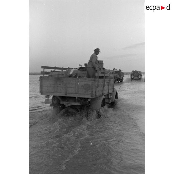 Passage de véhicules sur une piste inondée.