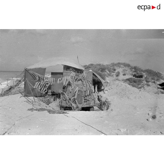 Un camion Opel Blitz est camouflé dans le sable près de la côte.