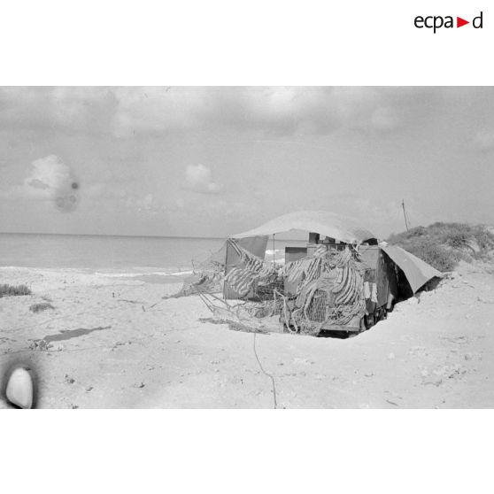 Un camion Opel Blitz est camouflé dans le sable près de la côte.