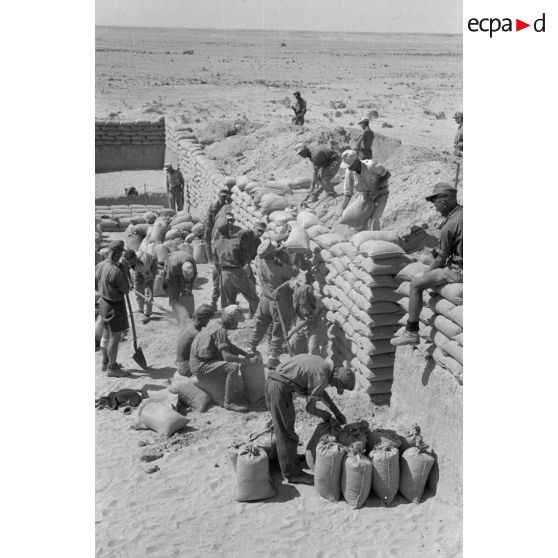 Construction d'un casernement avec des sacs de sable et une toile de tente.