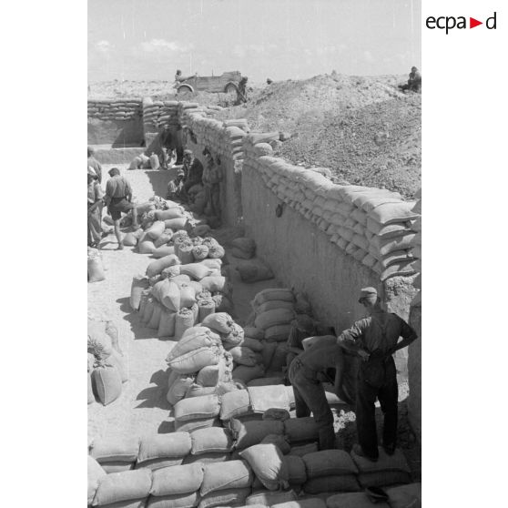 Construction d'un casernement avec des sacs de sable et une toile de tente.