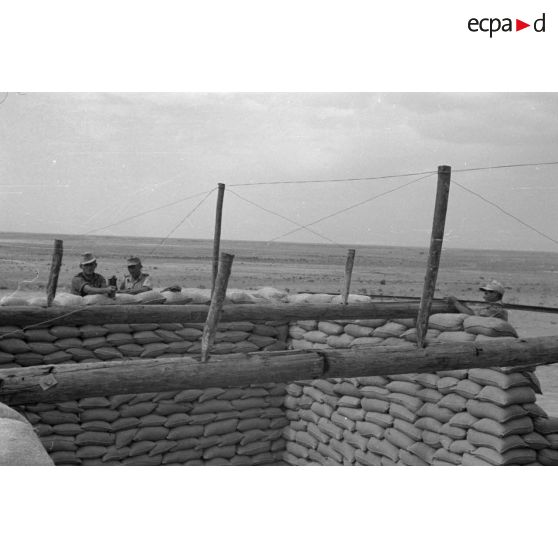 Construction d'un casernement avec des sacs de sable et une toile de tente.