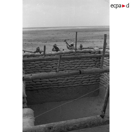 Construction d'un casernement avec des sacs de sable et une toile de tente.