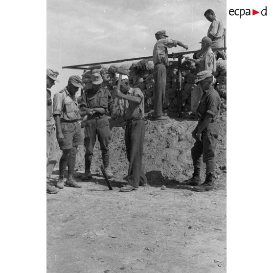 Construction d'un casernement avec des sacs de sable et une toile de tente.